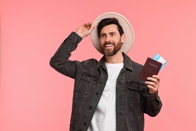 Smiling man with passport and tickets on pink background