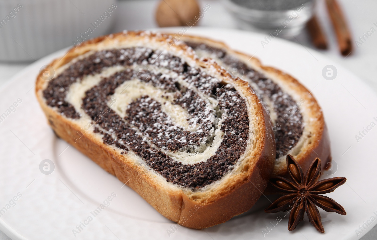 Photo of Slices of poppy seed roll and anise star on plate, closeup. Tasty cake