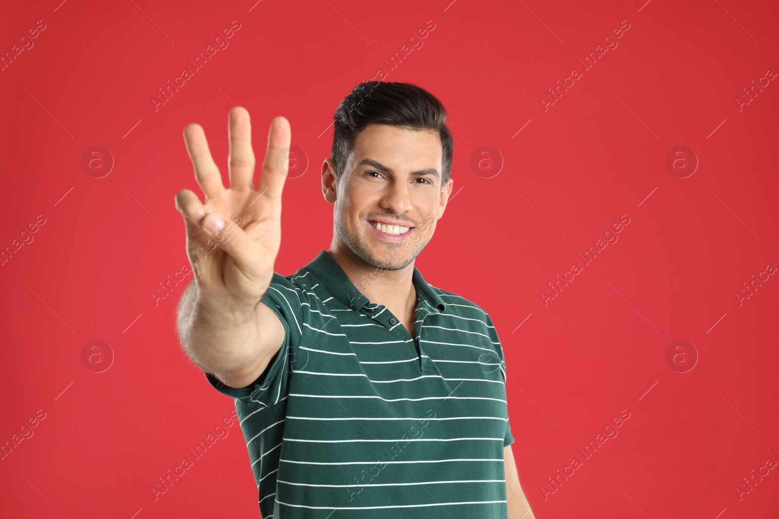 Photo of Man showing number three with his hand on red background