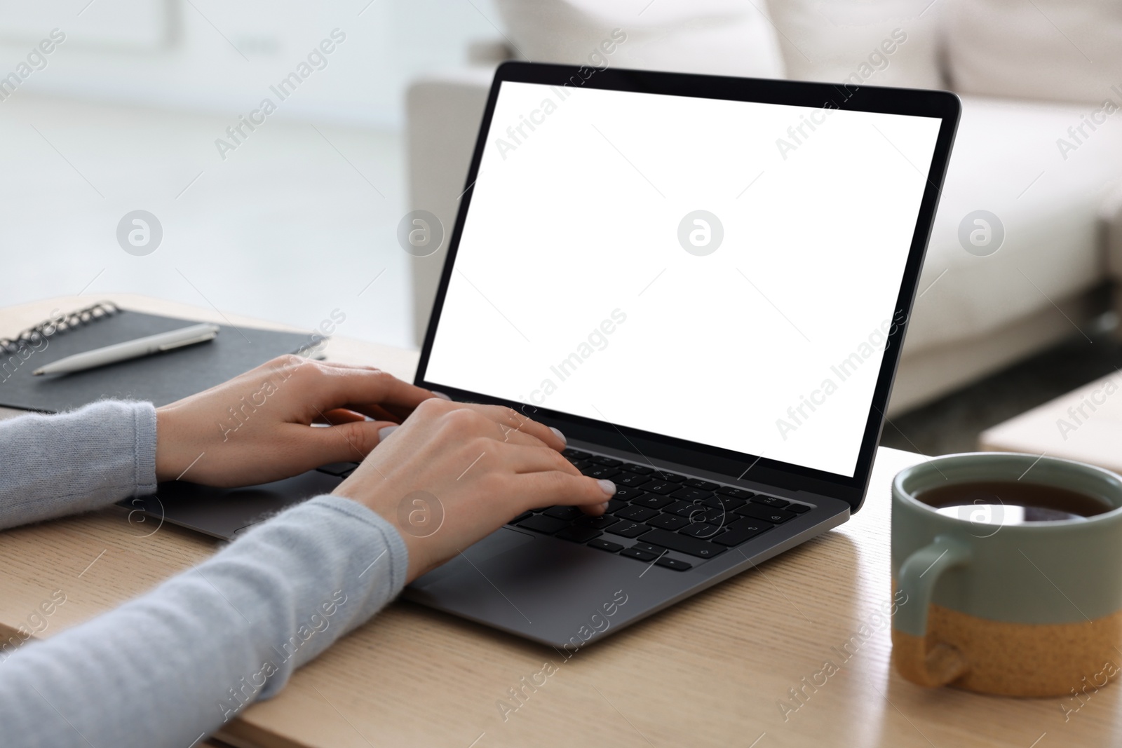 Photo of Woman working with laptop at wooden desk indoors, closeup