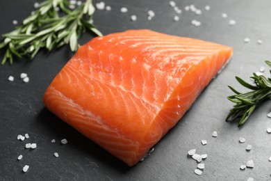 Photo of Fresh raw salmon and ingredients for marinade on black table