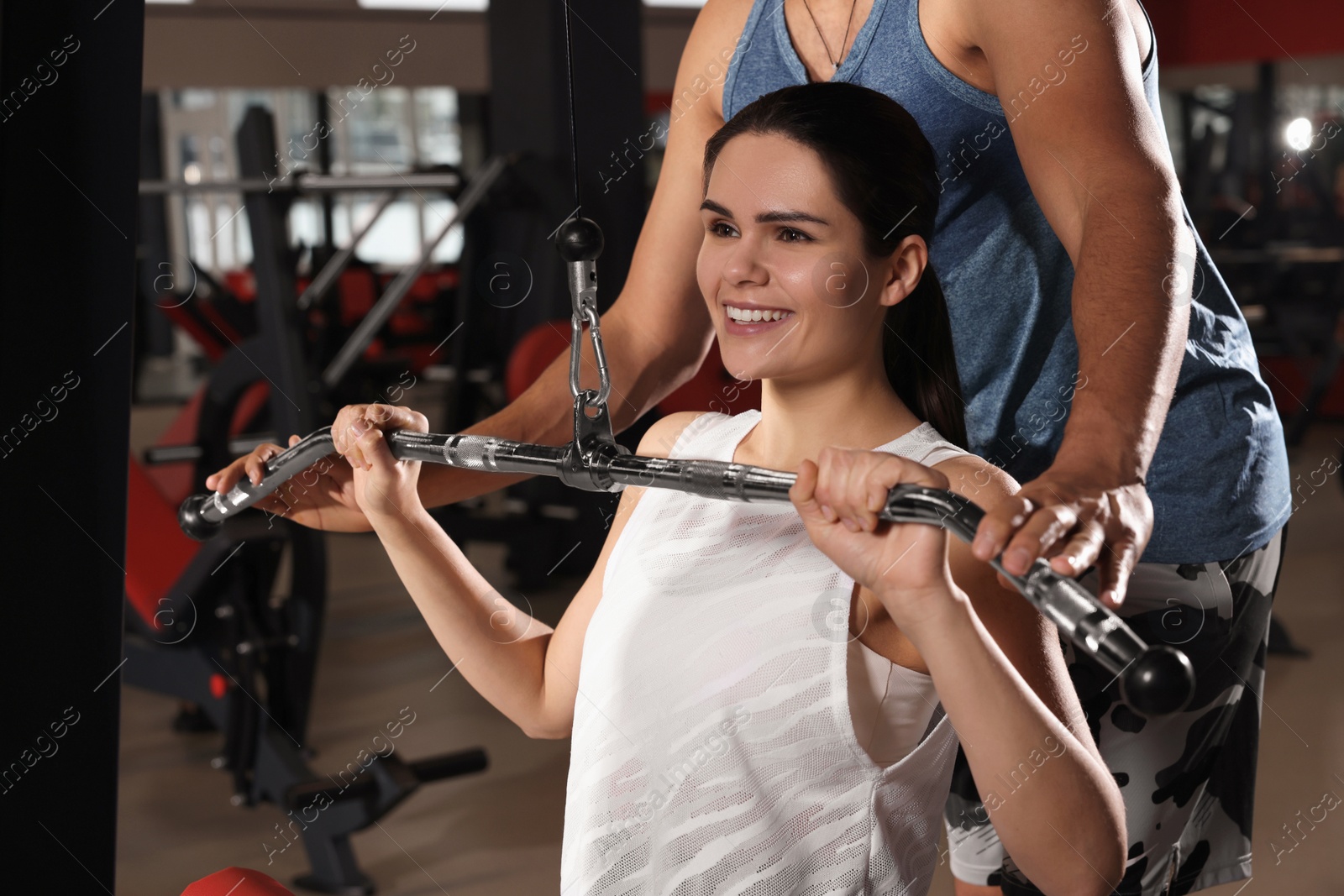 Photo of Young woman working out with professional trainer in modern gym