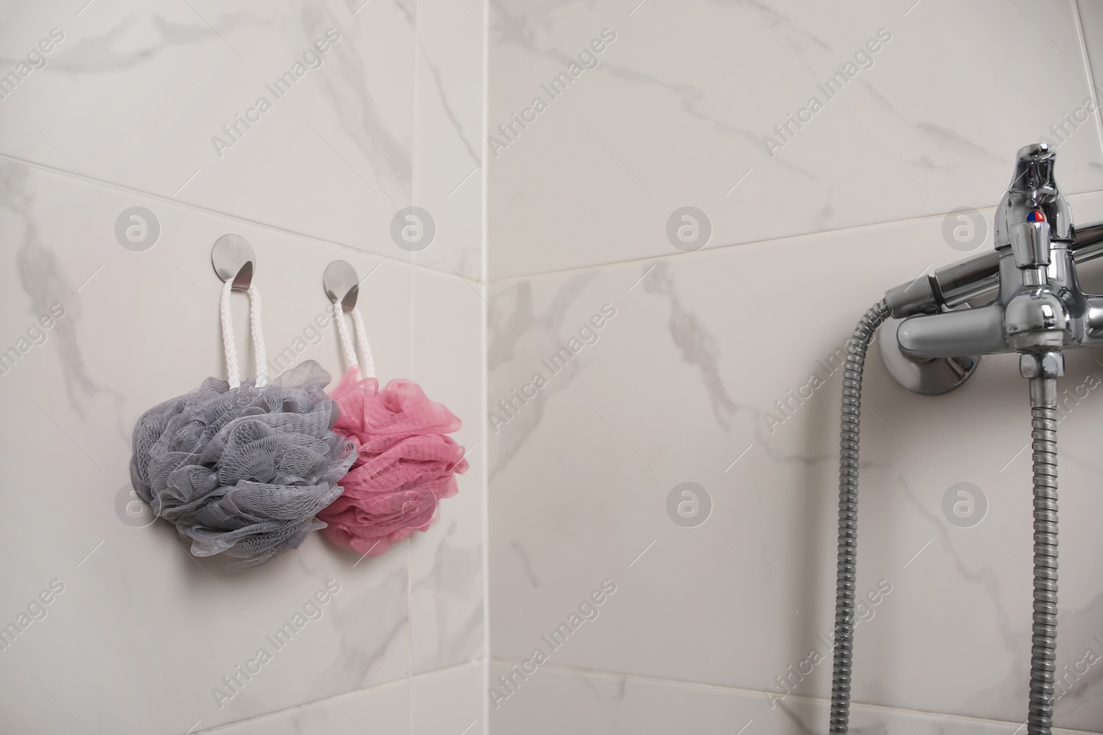 Photo of Shower puffs hanging near faucet in bathroom, space for text
