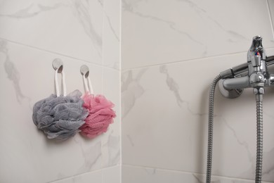 Shower puffs hanging near faucet in bathroom, space for text