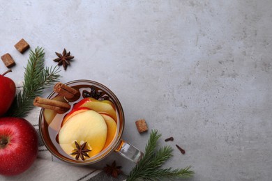 Aromatic hot mulled cider on grey table, flat lay. Space for text