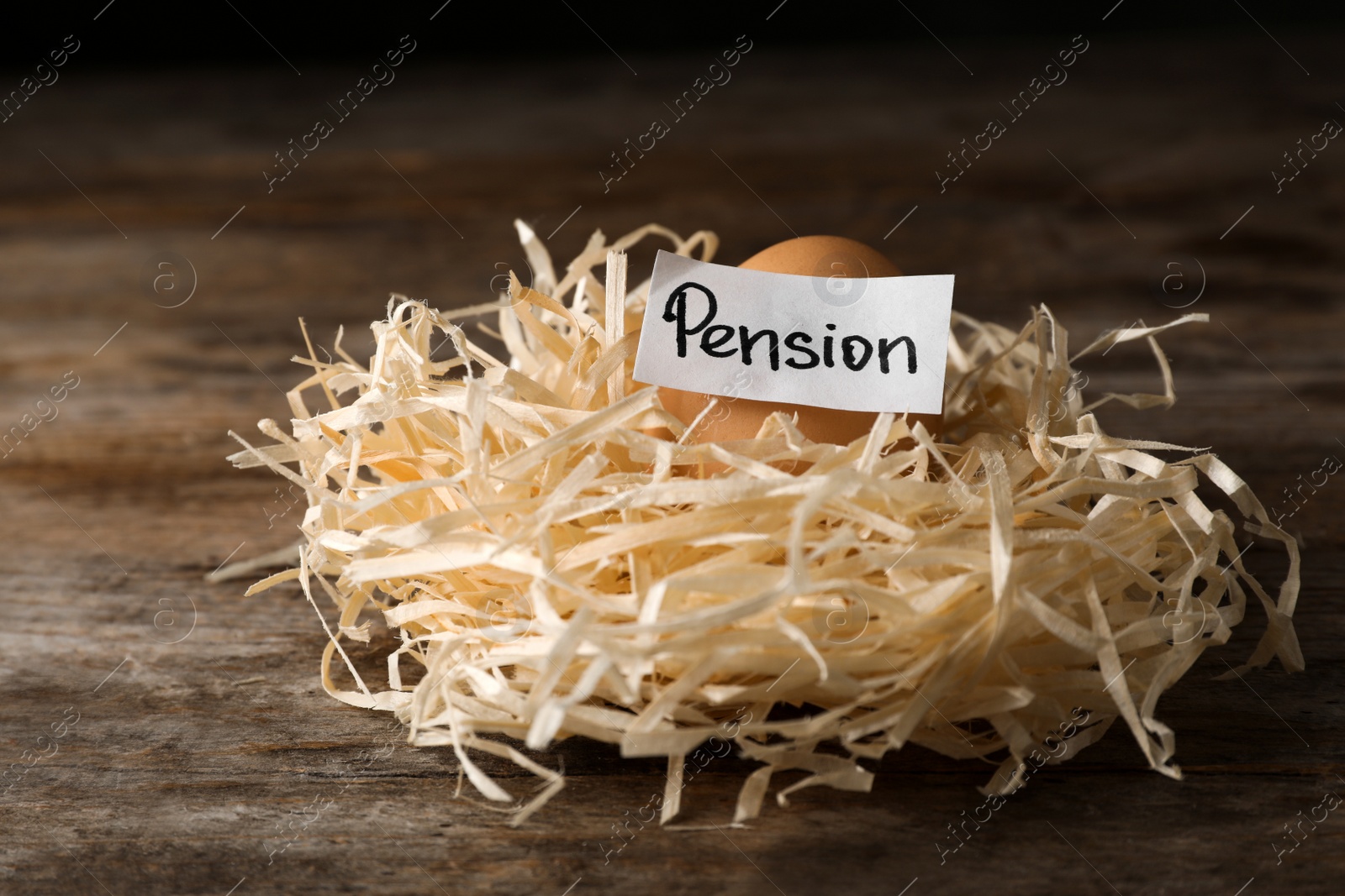 Photo of Egg and card with word PENSION in nest on wooden background