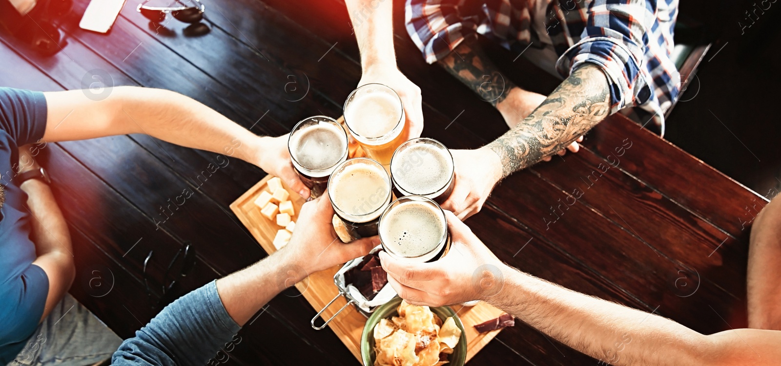 Image of Group of friends toasting with beer in pub, above view. Banner design