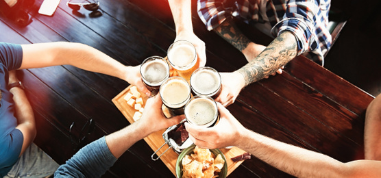 Group of friends toasting with beer in pub, above view. Banner design