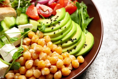 Delicious avocado salad with chickpea on grey table, closeup