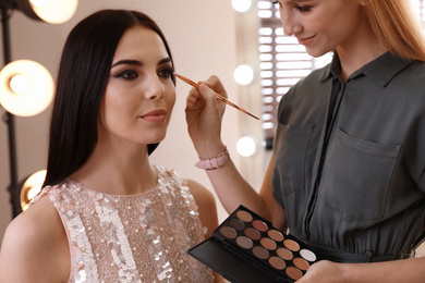 Professional makeup artist working with beautiful woman in salon