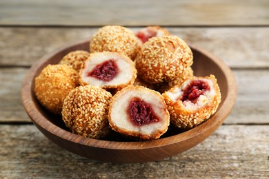 Delicious sesame balls with red bean paste on wooden table, closeup