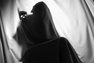 Photo of Silhouette of creepy ghost with skull behind grey cloth