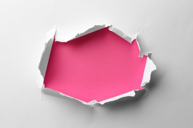 Hole in white paper on pink background