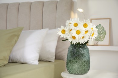 Bouquet of beautiful daisy flowers on table in bedroom, space for text