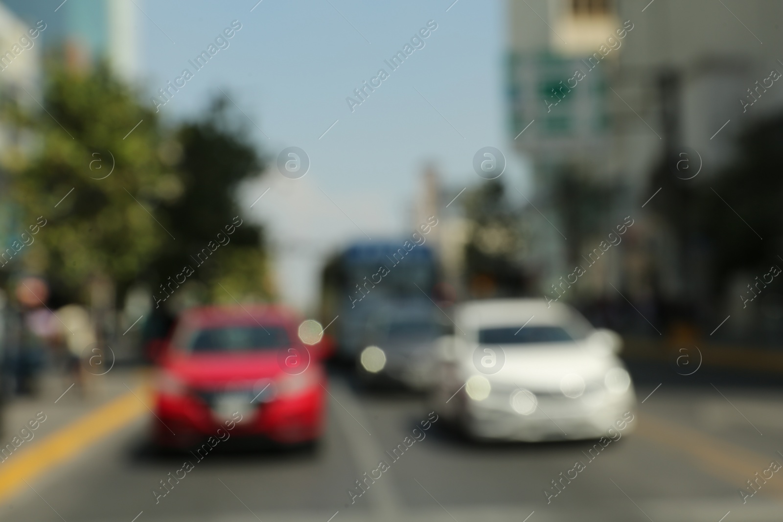 Photo of Blurred view of city street with buildings and parked cars