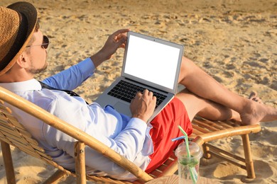 Man with laptop sitting on sandy beach. Business trip