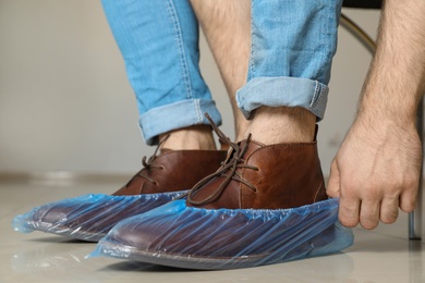 Photo of Man putting on blue shoe covers, closeup