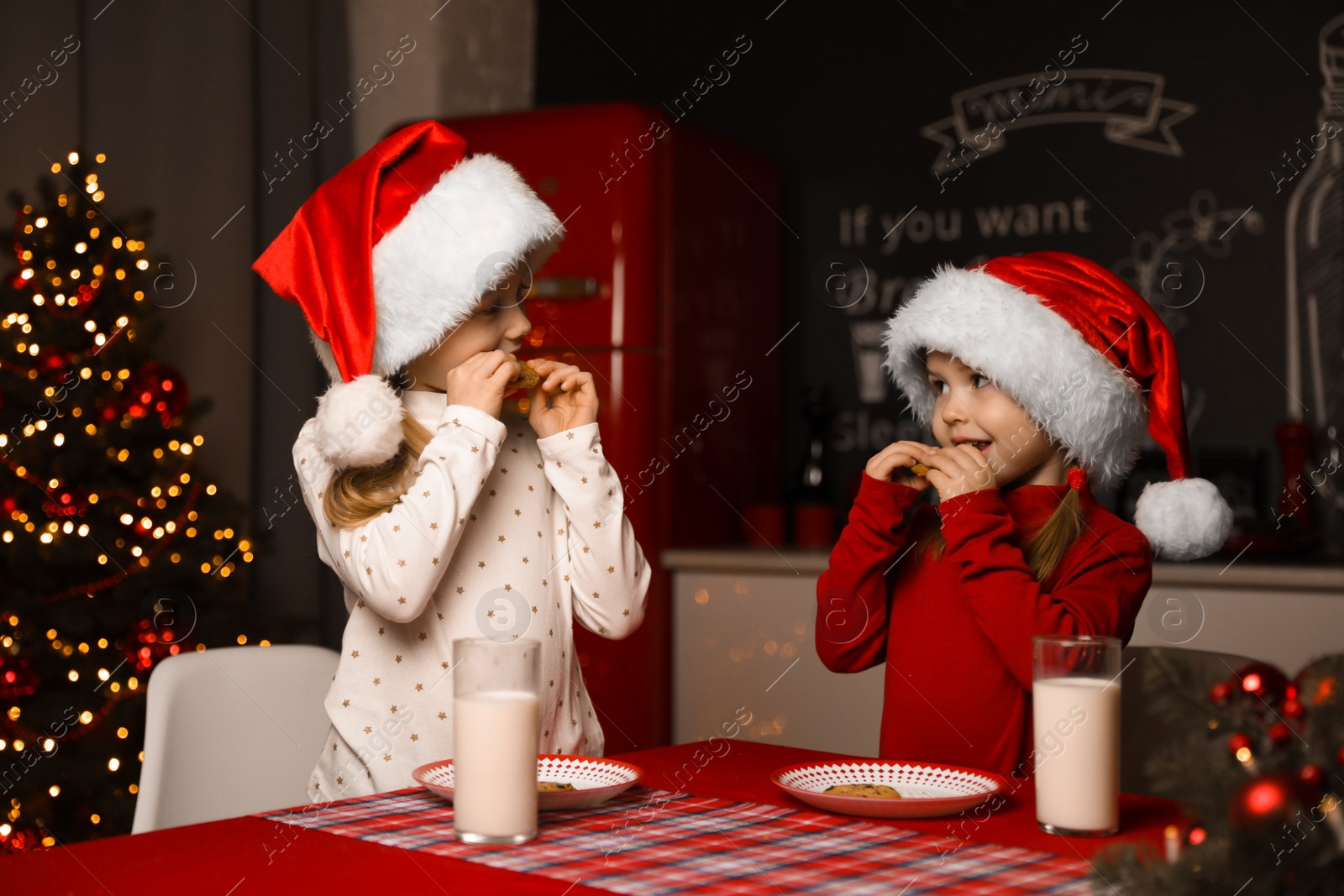 Photo of Cute little children at table in dining room. Christmas time