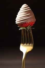 Photo of Fork with chocolate covered strawberry on dark background, closeup