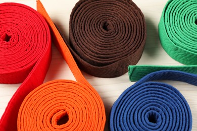 Photo of Colorful karate belts on wooden background, closeup