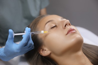 Beautiful woman getting facial injection in salon