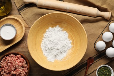 Photo of Bowl with flour and different products on wooden table, flat lay