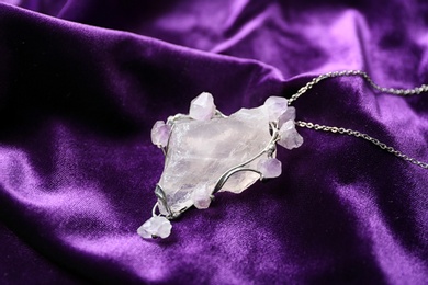 Beautiful silver pendent with pure quartz and amethyst gemstones on violet fabric