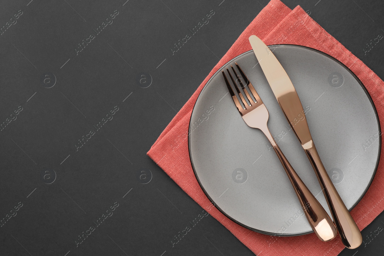 Photo of Clean plate, cutlery and napkin on grey table, top view. Space for text