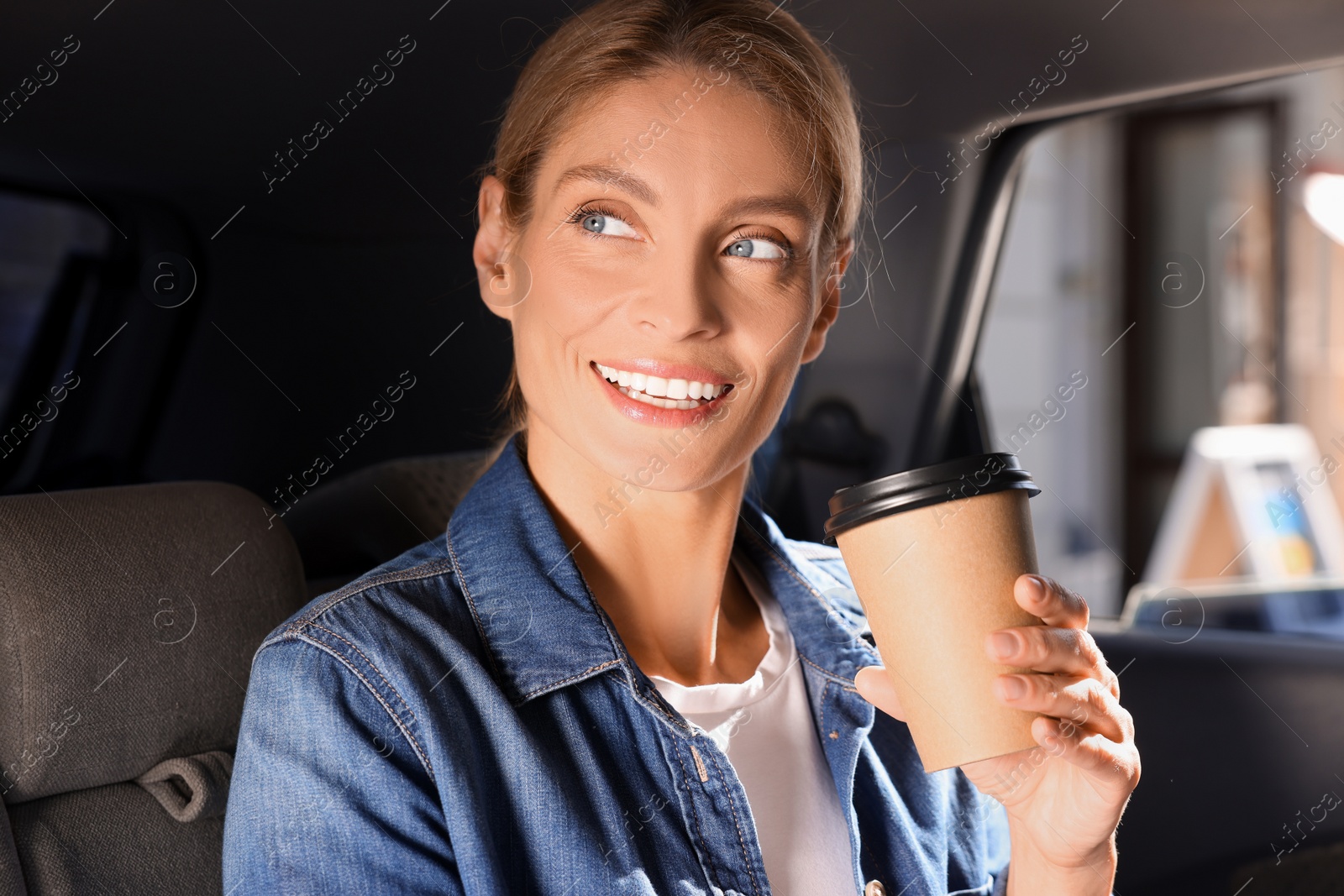 Photo of Coffee to go. Happy woman with paper cup of drink in car