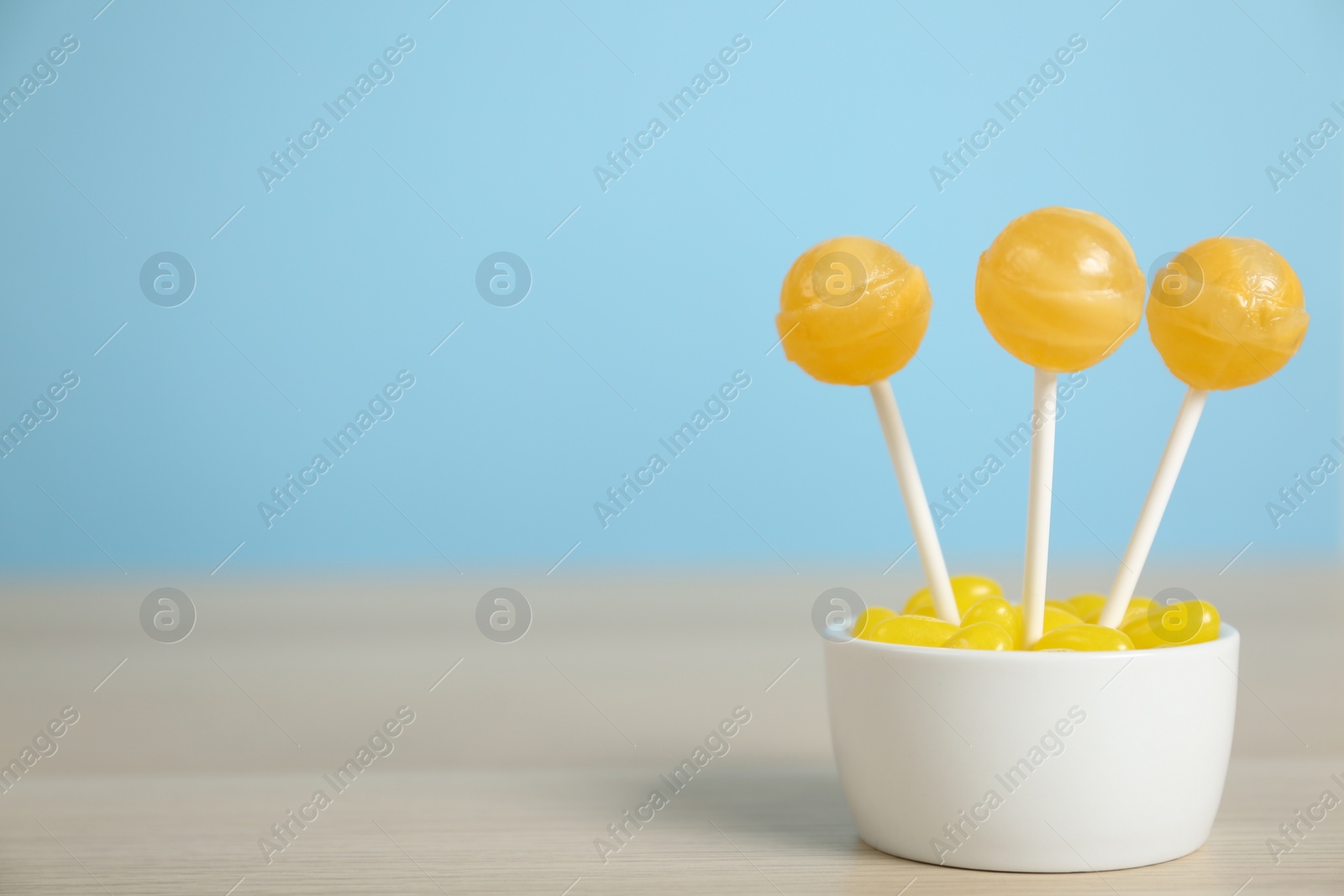 Photo of Different lemon candies on wooden table. Space for text