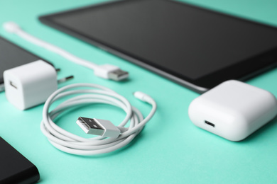 Photo of USB charge cable and gadgets on light blue background, closeup