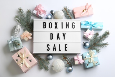 Photo of Lightbox with phrase BOXING DAY SALE and Christmas decorations on white background, flat lay