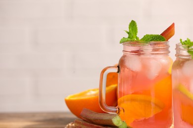 Mason jars of tasty rhubarb cocktail with citrus fruits on table, closeup. Space for text