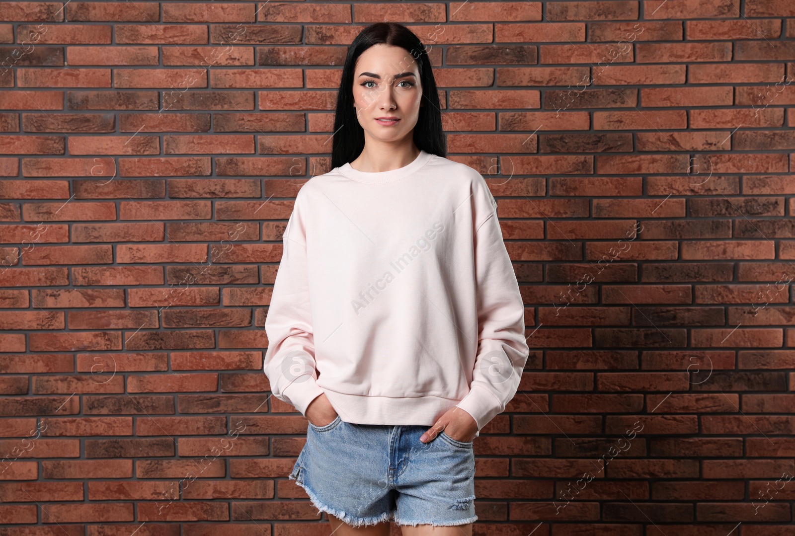 Photo of Portrait of young woman in sweater at brick wall. Mock up for design