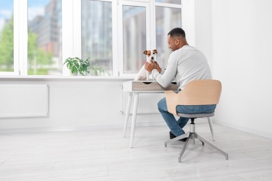 Photo of Young man with Jack Russell Terrier at desk in home office