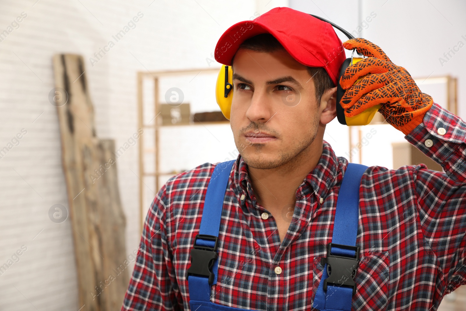 Photo of Worker wearing safety headphones indoors, space for text. Hearing protection device