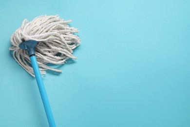 Photo of Mop with plastic handle on light blue background, top view. Space for text