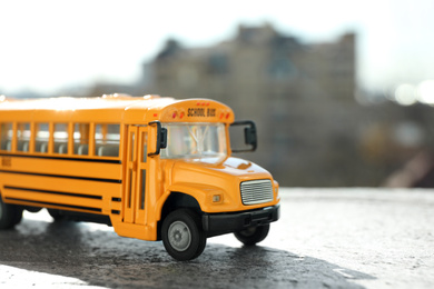 Photo of Yellow toy school bus on road outdoors. Student's transport