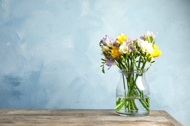 Photo of Bouquet of fresh freesia flowers in vase on table. Space for text