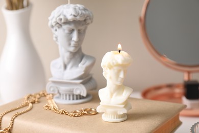 Photo of Beautiful David bust candles and book on dressing table