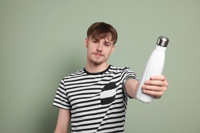 Man holding thermo bottle with drink on olive background