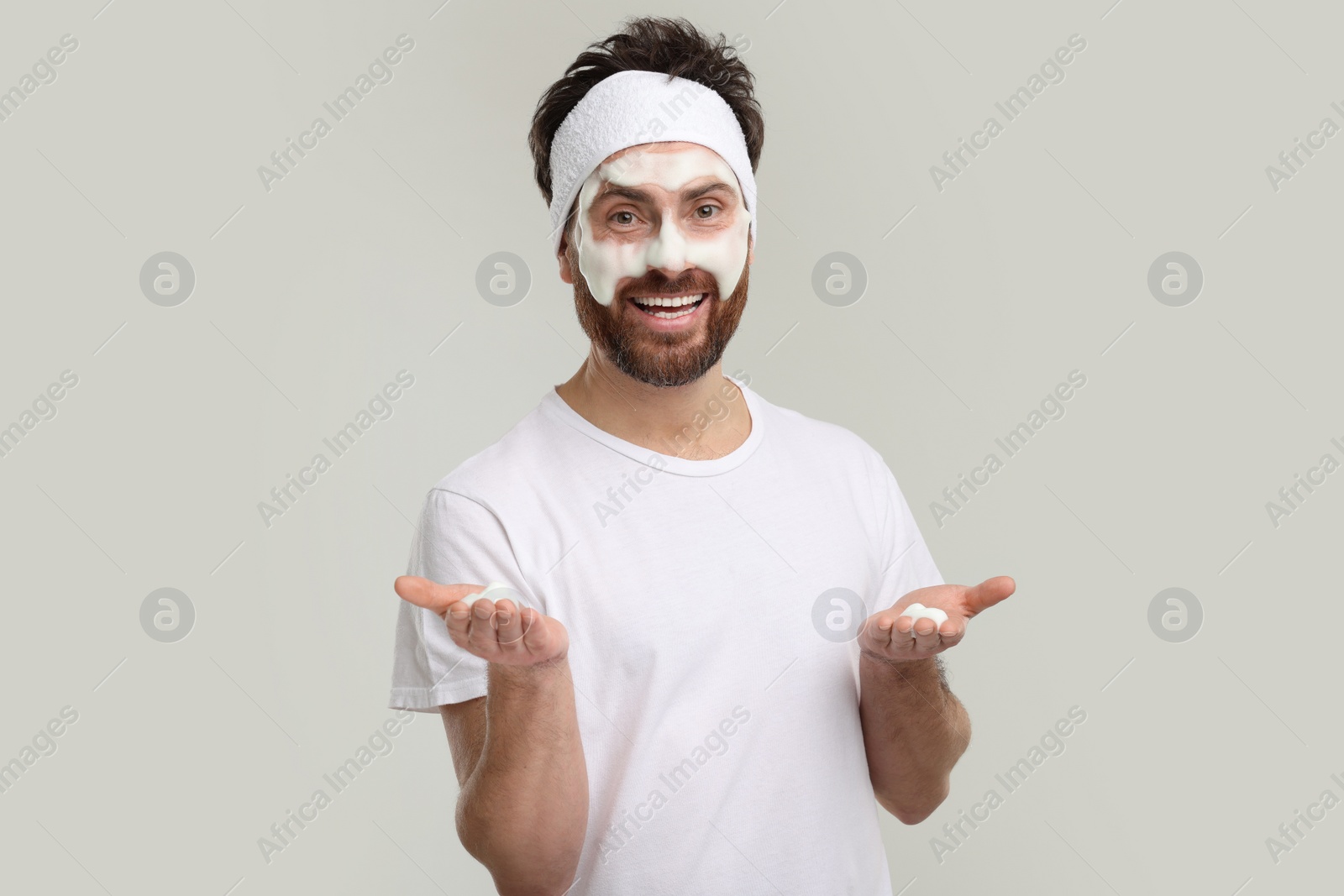 Photo of Man with headband washing his face on light grey background