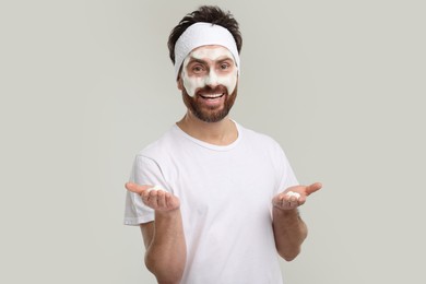 Man with headband washing his face on light grey background