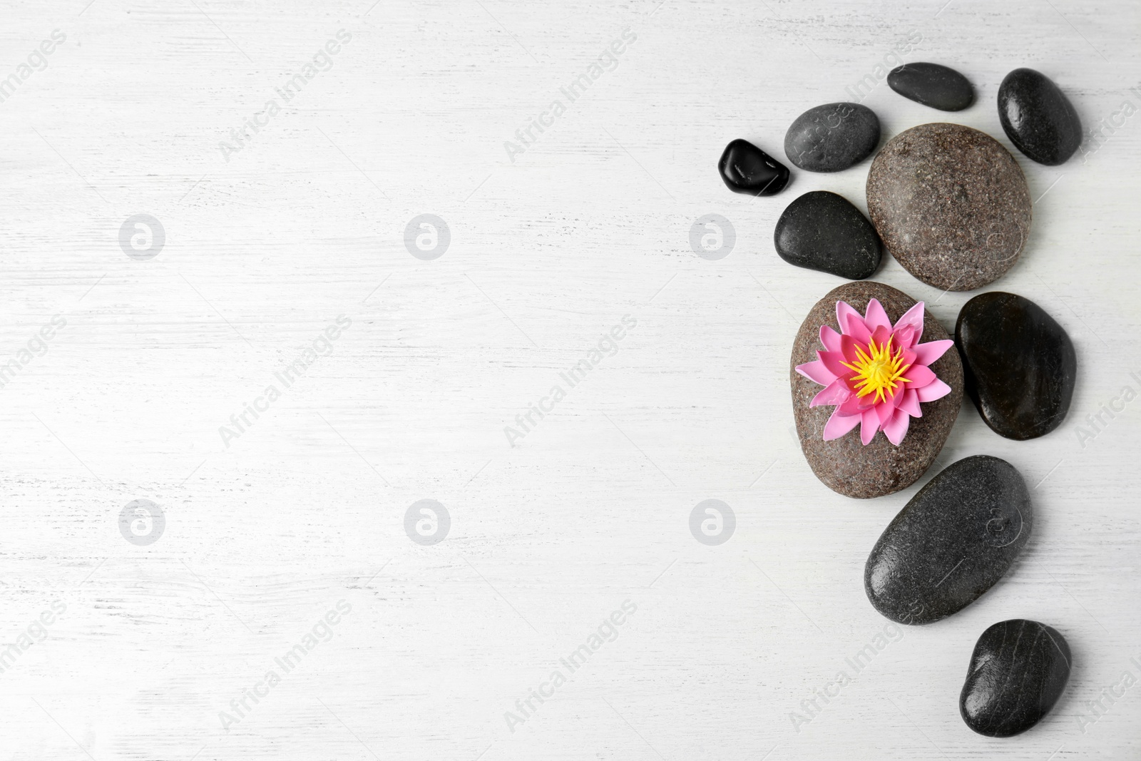 Photo of Stones with lotus flower and space for text on white wooden background, flat lay. Zen lifestyle