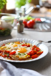 Plate of tasty fried eggs with vegetables on table in kitchen. Space for text