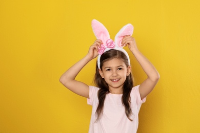 Photo of Portrait of little girl in Easter bunny ears headband on color background