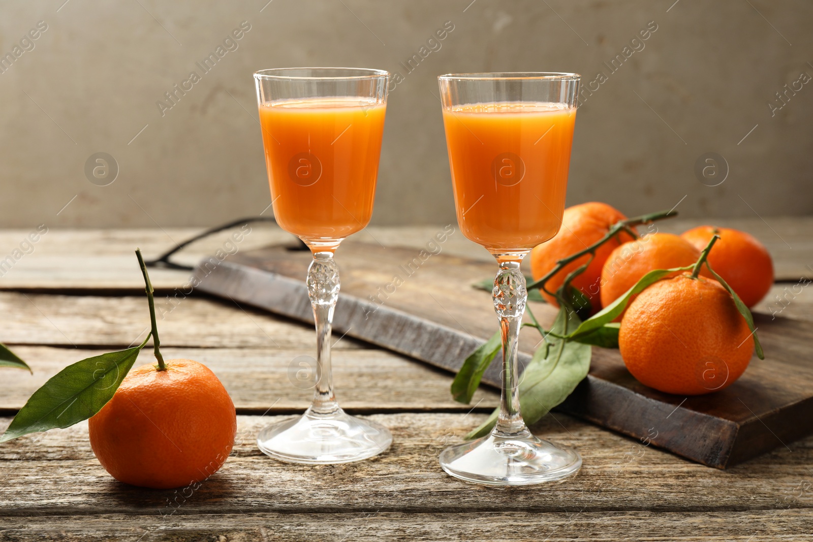 Photo of Delicious tangerine liqueur and fresh fruits on wooden table