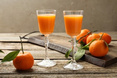 Delicious tangerine liqueur and fresh fruits on wooden table