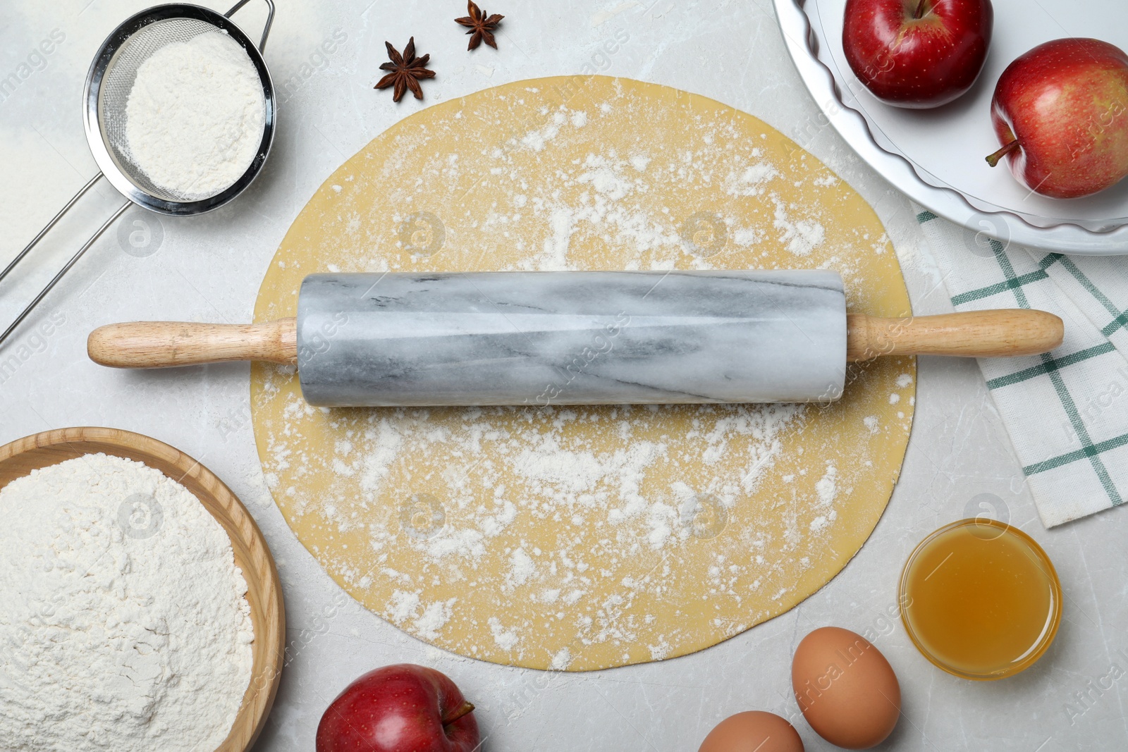 Photo of Flat lay composition with raw dough and ingredients on light grey table. Baking apple pie