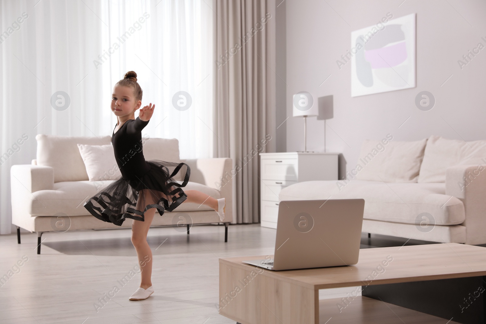 Photo of Cute little girl taking online dance class at home